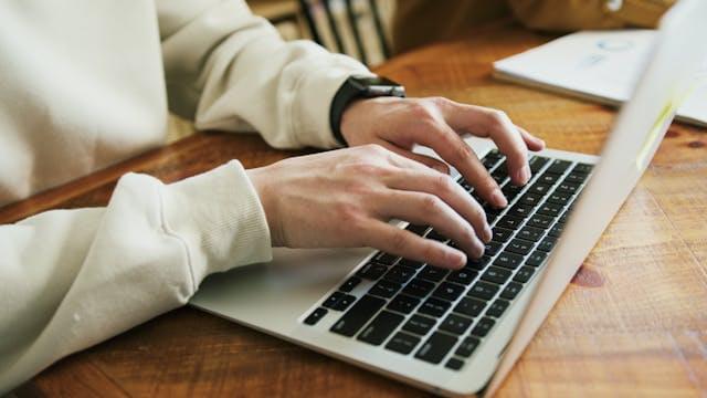 Руки печатают текст запроса на ноутбуке